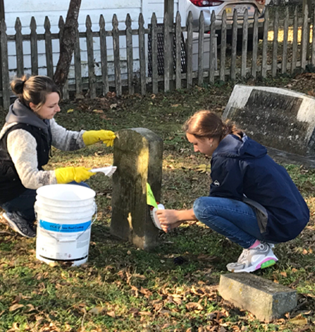 Two young girls cleaning headstones at the Parsons Cemetery
