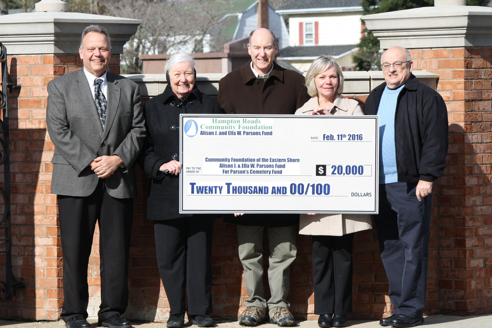 five people holding a large check for twenty thousand dollars